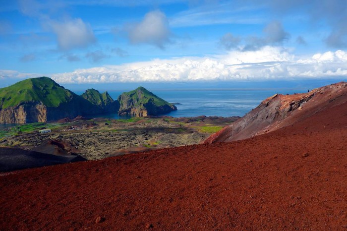 Red lava rocks green mountains bright blue water put ithellip